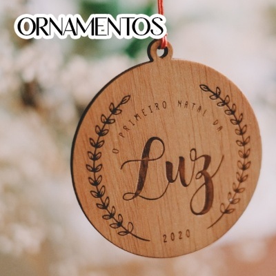 Ornamento de madeira redondo gravado com texto e pendurado por fio vermelho