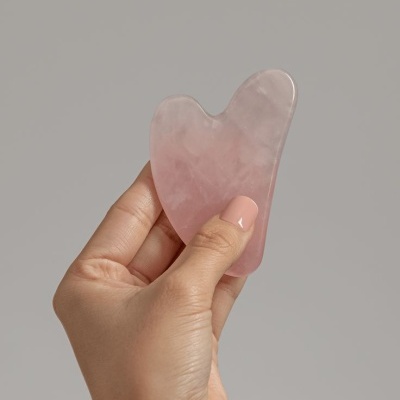 Ferramenta de massagem facial em quartzo rosa na mão