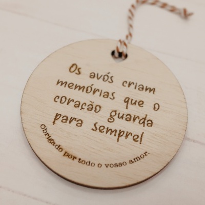 Medalhão em madeira redondo com gravação em português e cordão, sobre superfície de madeira branca