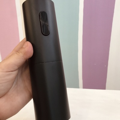 Dispositivo cilíndrico preto com botão retangular e fundo colorido