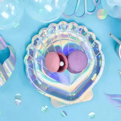 Prato iridescente formato concha com dois macarons e decoração azul com balões.