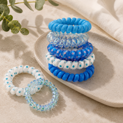 Elásticos de cabelo em espiral coloridos e estampados sobre prato cerâmico e superfície clara
