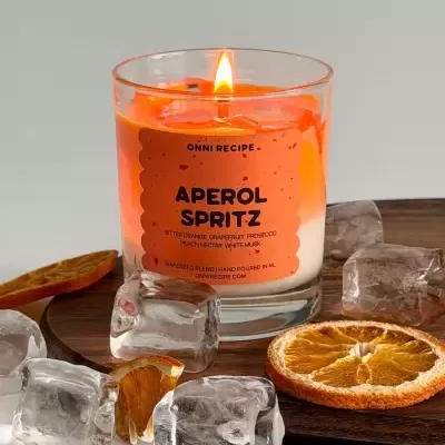 Vela Aperol Spritz num copo de vidro com cubos de gelo e fatias secas de laranja