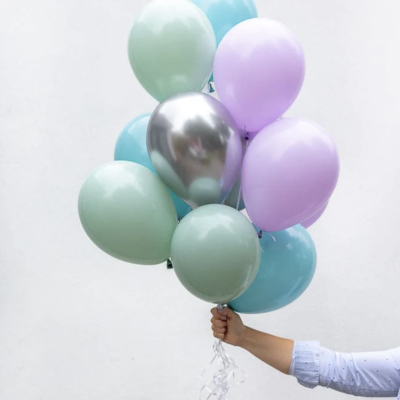Balões coloridos azul, verde, lilás e prateado amarrados e segurados na mão