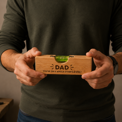 Nível de bolha em madeira com mensagem para pai sendo segurado por homem em ambiente de oficina