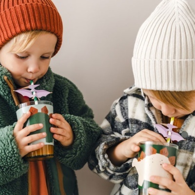 Crianças com gorros e casacos segurando copos com canudo e decoração de flores