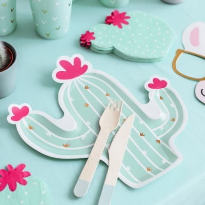 Prato descartável em forma de cacto com talheres de madeira sobre mesa azul clara