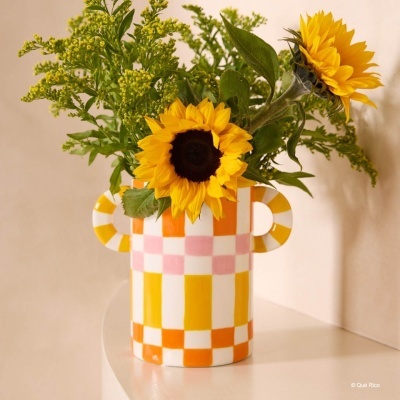 Jarro cerâmico quadriculado laranja, amarelo e rosa com flores girassóis amarelos e folhagem verde