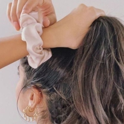 Elástico de cabelo creme tipo scrunchie usado no pulso