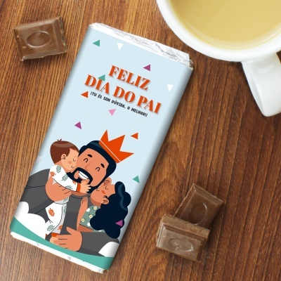 Chocolate com embalagem comemorativa de Dia do Pai ao lado de pedaços de chocolate e copo com bebida