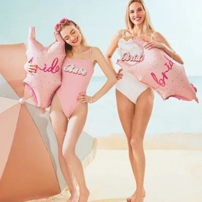 Duas mulheres em maiôs segurando bóias infláveis na praia