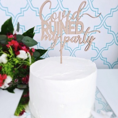 Bolo branco simples com decoração em madeira e flores ao lado