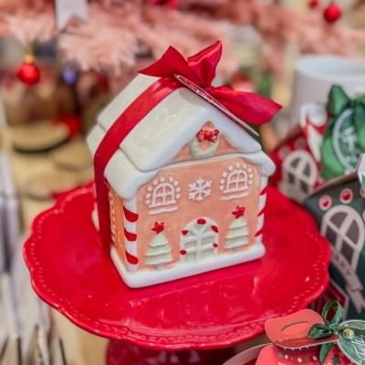 Caixa decorativa em forma de casa de gengibre com laço vermelho sobre prato vermelho