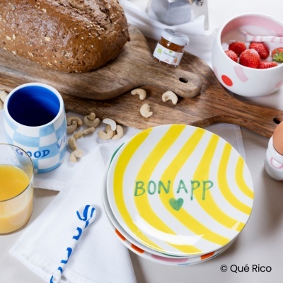 Mesa de pequeno-almoço com pão, prato BON APP amarelo, caneca GOOD VIBES e morangos