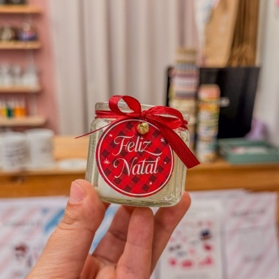 Vela de Natal em frasco de vidro com fita vermelha e etiqueta com Feliz Natal