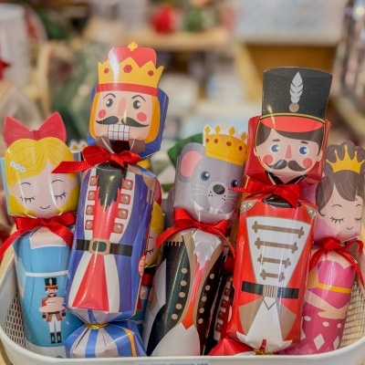 Embrulhos coloridos com personagens de soldado, rato e princesa numa caixa branca