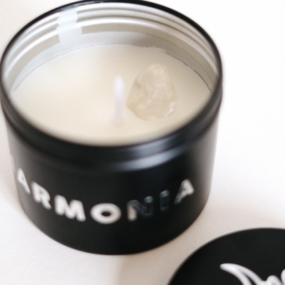 Vela branca em frasco preto com a palavra 'ARMONIA' e tampa preta com desenho branco