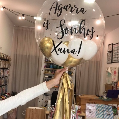 Balão transparente com texto preto e balões dentro, em loja decorada