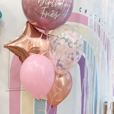 Conjunto de balões rosa e dourado metálico com mensagem de aniversário em parede decorada