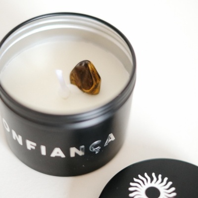 Vela branca em lata preta com pedra castanha no centro e tampa preta com desenho branco