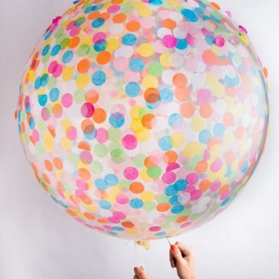 Balão transparente grande com confetis coloridos redondos segurado por duas mãos