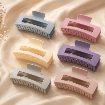Seis presilhas de cabelo retangulares em plástico mate e cores pastel sobre tecido acetinado champanhe