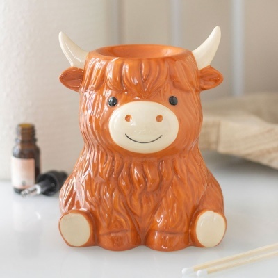 Vela de cerâmica em forma de vaca ou touro castanha sorridente com cornos brancos