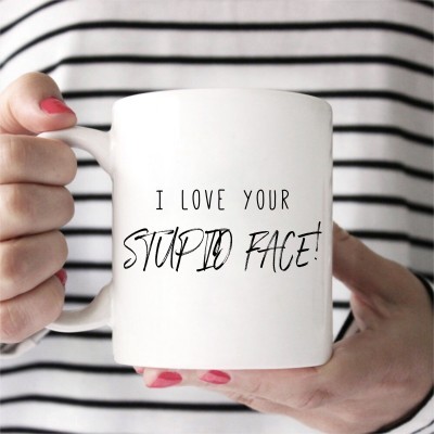 Caneca branca com frase em inglês segurada por pessoa com camisola às riscas