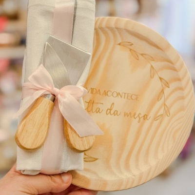 Conjunto de tábua redonda de madeira clara com utensílios e guardanapo