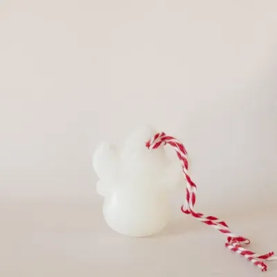 Vela branca em forma de anjo com corda vermelha e branca
