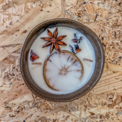 Vela artesanal com anis e decoração em cerâmica castanha sobre madeira rústica