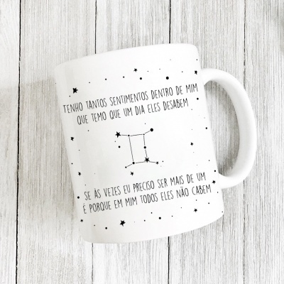 Caneca branca com texto em português e desenho da constelação de Gêmeos
