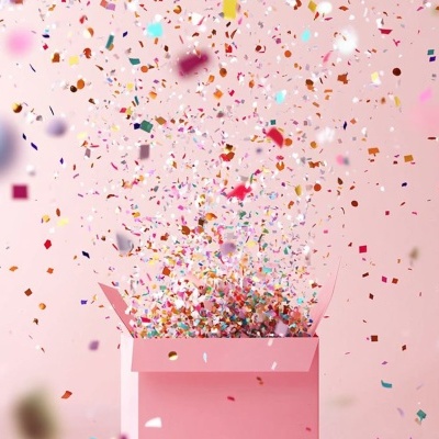 Caixa rosa aberta com confetes coloridos a sair