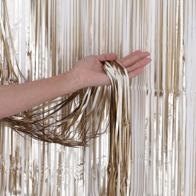 Mão segurando fitas metálicas douradas e prateadas em fita cortina brilhante