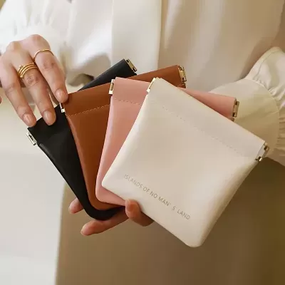 Carteiras pequenas quadradas em quatro cores com acabamento liso e texto dourado na carteira branca