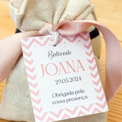 Saco de tecido com etiqueta de batizado rosa e branco com texto em português