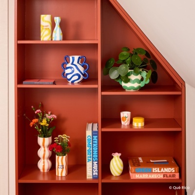 Estante vermelha com vasos cerâmicos coloridos e livros de viagem