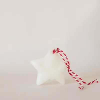 Vela branca em forma de estrela com cordão vermelho e branco