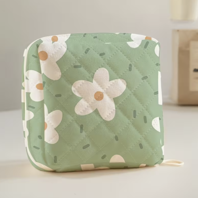 Bolsa quadrada verde com flores brancas e detalhes matelassê.