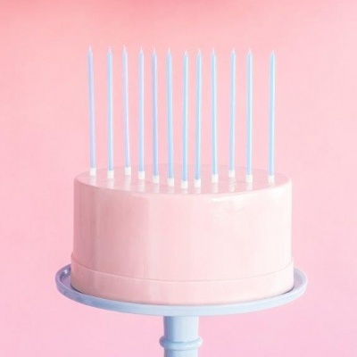 Bolo rosa com doze velas azuis num suporte azul