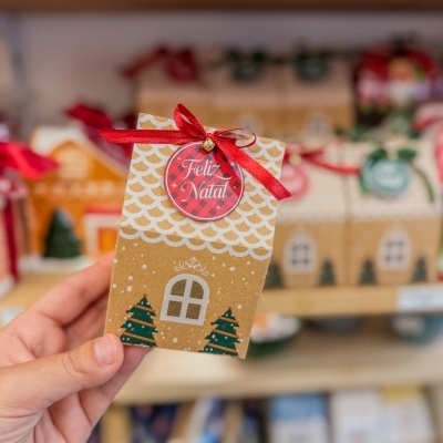 Caixa de presente de papel decorada com tema de Natal e laço vermelho