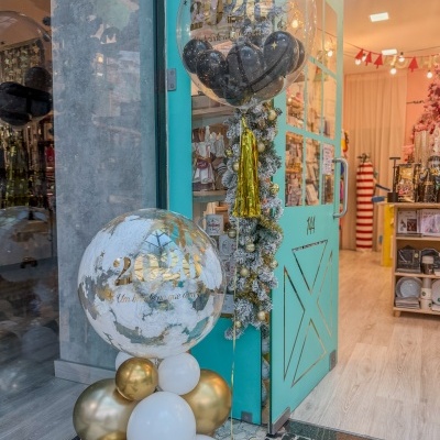Decoração com balões para festa de 2026 na entrada de loja com porta azul-turquesa