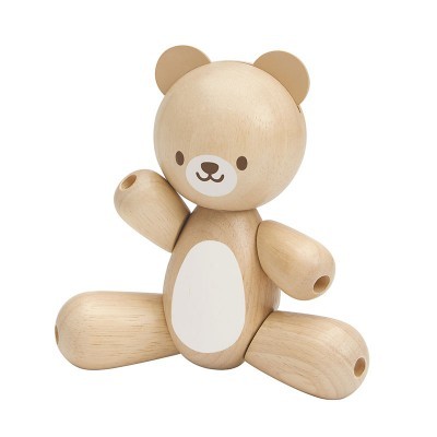 Urso de brinquedo de madeira claro com manchas brancas sentado, design minimalista
