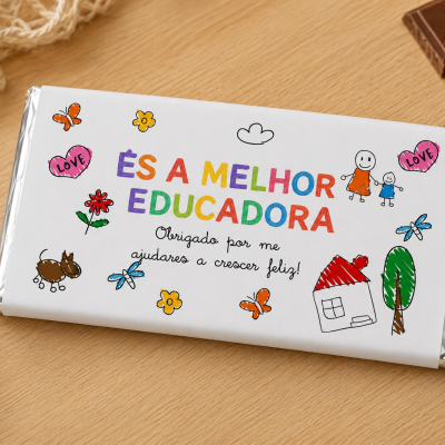 Barra de chocolate com embalagem branca e texto colorido ÉS A MELHOR EDUCADORA, desenhos infantis coloridos, sobre mesa de madeira clara.