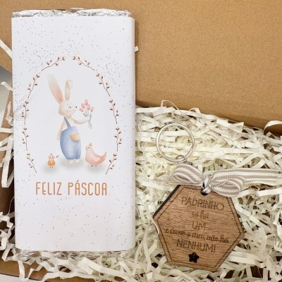 Embalagem de chocolate com ilustração de coelho e porte-chaves em madeira com fita e texto para padrinho