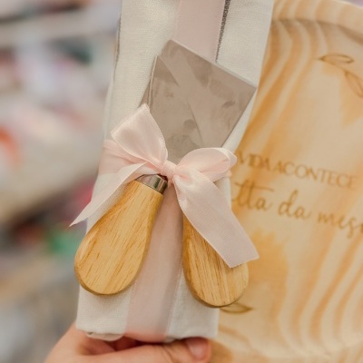 Conjunto de faca e garfo para queijo com cabo de madeira e pano de cozinha com laço rosa e tábua de cortar