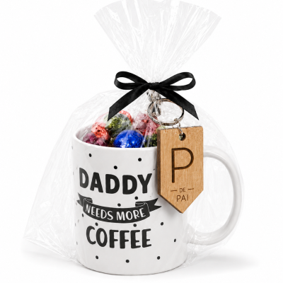 Caneca branca com texto Daddy needs more coffee, embalada em plástico transparente com laço preto e chaveiro com etiqueta de madeira P de Pai e bombons dentro.