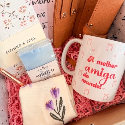 Caixa de oferta com caneca, carteira, sabonete, caneta, meias bordadas e papel de seda cor-de-rosa.