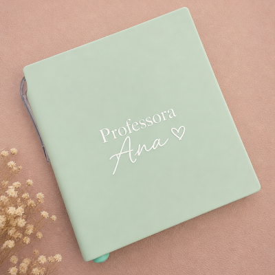 Caderno capa verde com texto Professora Ana e coração, flores secas e teclado