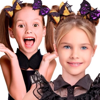 Duas crianças com fatos pretos e acessórios de cabelo com morcegos brilhantes